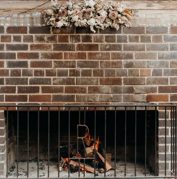 The brick fireplace lit, dried florals on the mantel