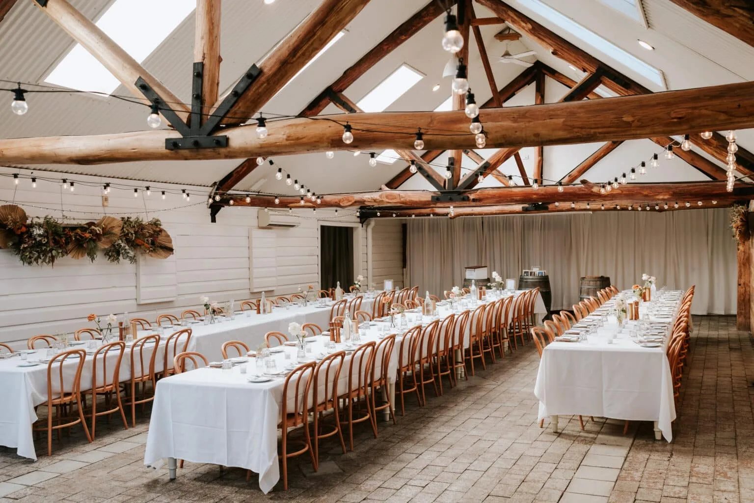 The Carrington Room dressed for a wedding, long white tables and exposed trusses