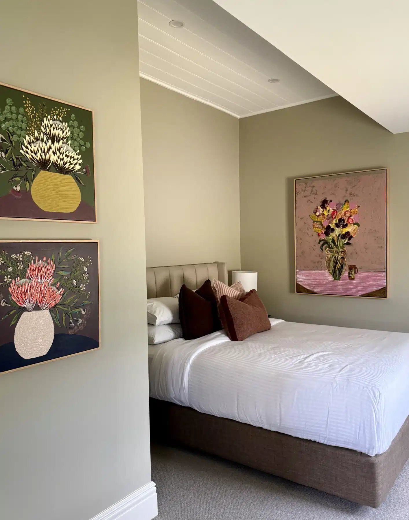 A room upstairs with a painting over the bed