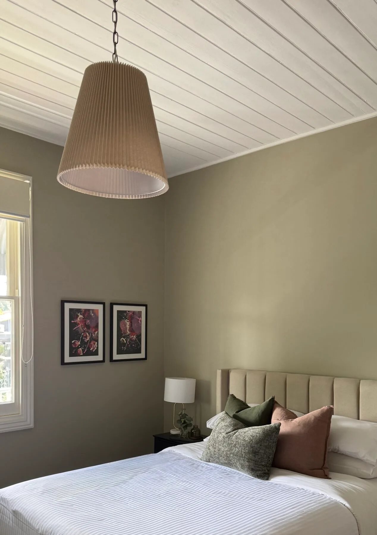 A sage-walled room upstairs, pendant light and bed